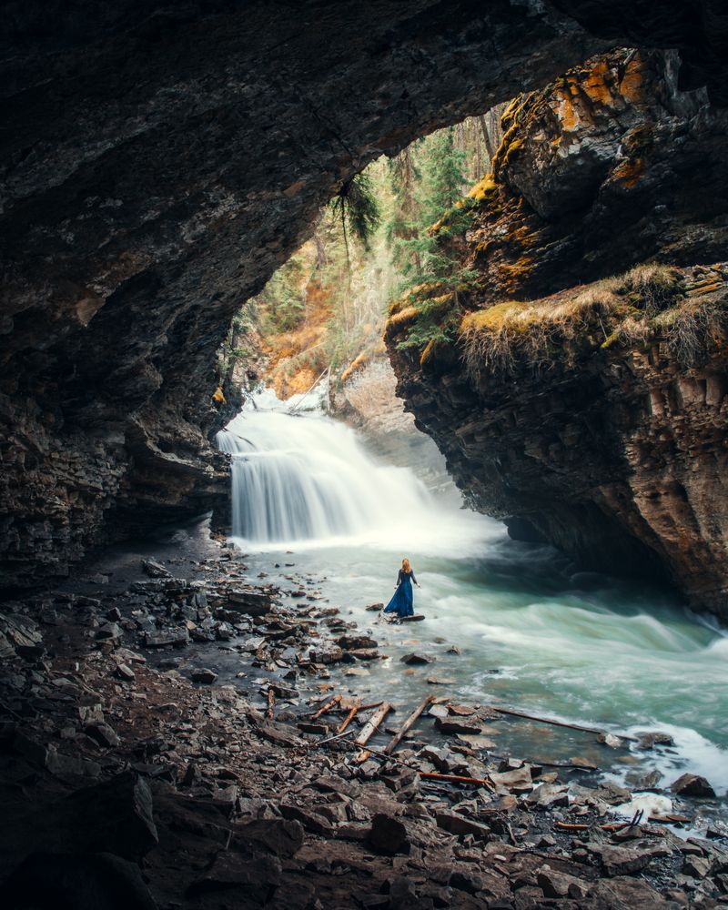 Woman in blue dress standing near waterfalls