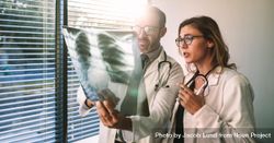 Doctors colleagues look at the x-ray of the patient and discussing the prognosis 47e2P0