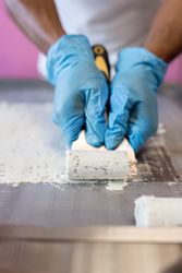 A worker is using a spatula to roll an ice cream on a freeze machine