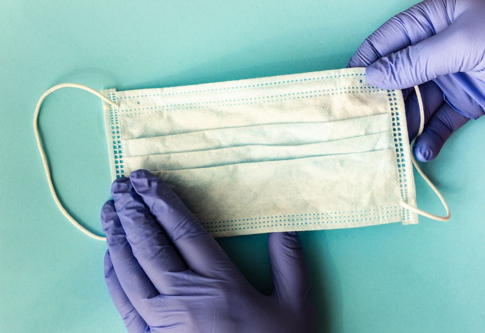 Covid-19 virus concept of looking down at hands in latex gloves with protective facemask