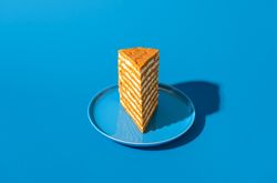 Honey layered cake slice, russian recipe, isolated on a blue background