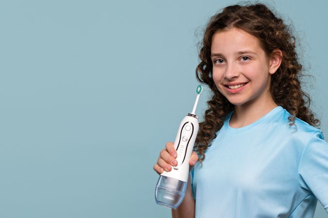 Smiling young girl holding electric toothbrush