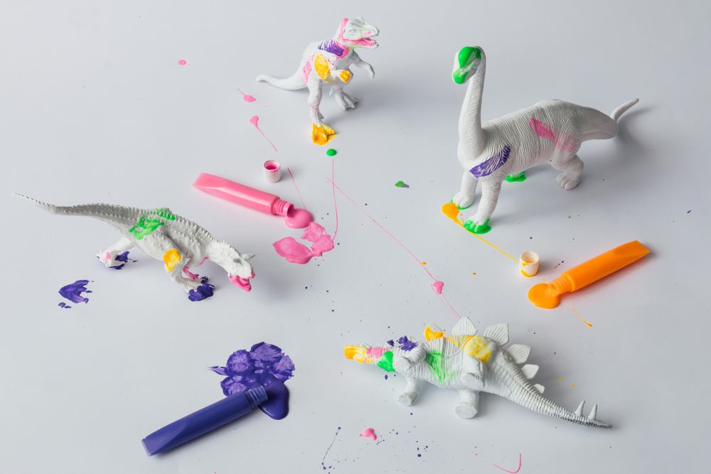 Plastic dinosaur splattered with different colors of paint