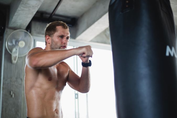 Muscular man doing boxing training in gym