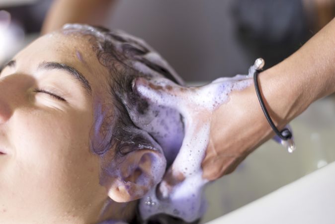 Female with head back and eyes closed having hair washed in salon