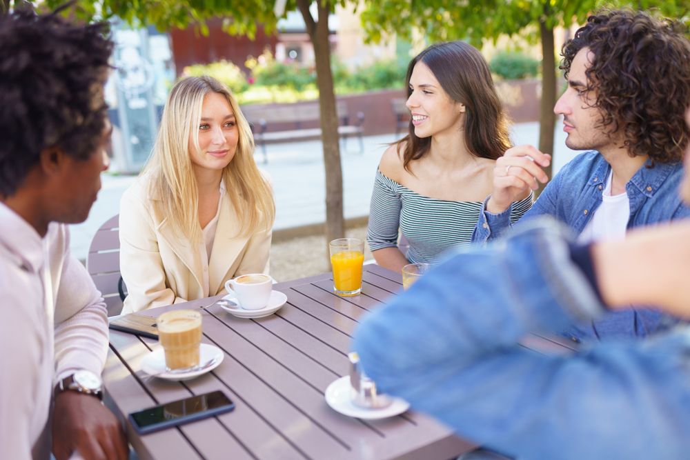 Friends having a conversation over coffee and juice at outside table