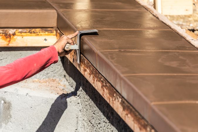 Construction Worker Using Stainless Steel Edger On Wet Cement Forming Coping Around New Pool