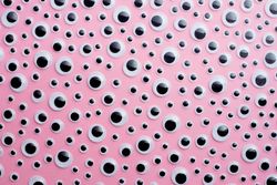 Scattered googly eyes on pink background
