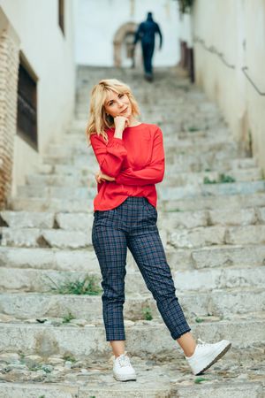 Smiling blonde woman with red shirt standing on steps outdoors
