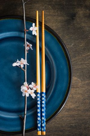 Close up of table setting with chop sticks on ceramic navy plate and delicate cherry blossom branch