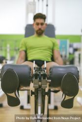Active male in green t-shirt working out quads using gym equipment 4dV2d0