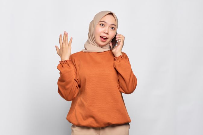 Muslim woman chatting expressively on cell phone