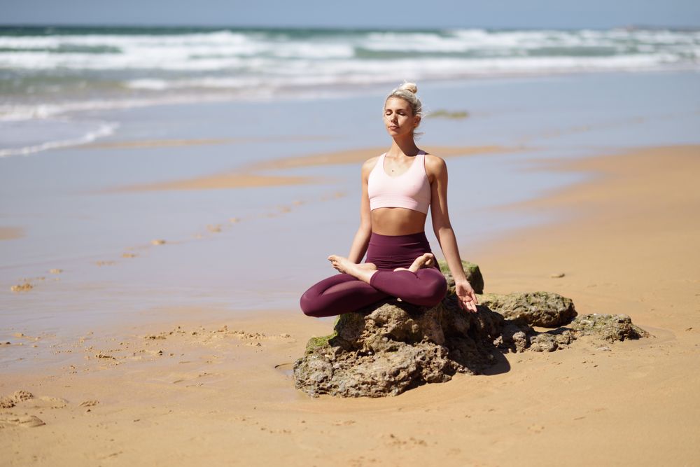 Woman sitting on a rock, meditating on a Spanish beach