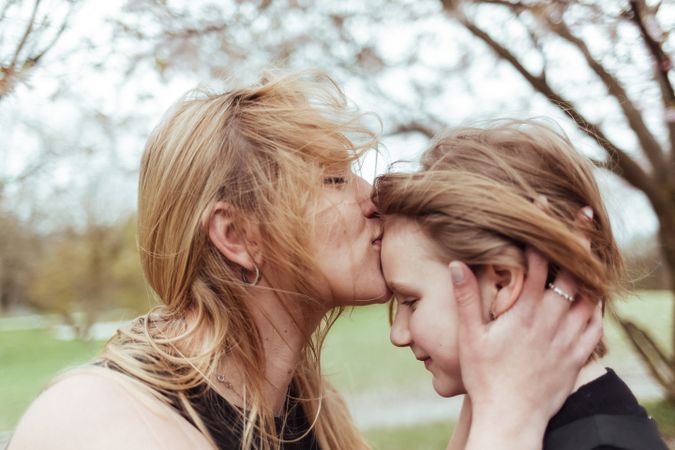 Woman kissing girl in park