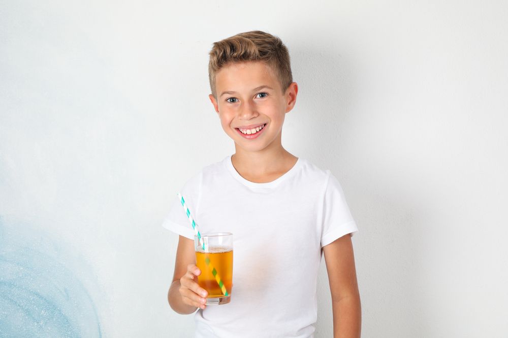 Smile boy with sweet cocktail against blank background