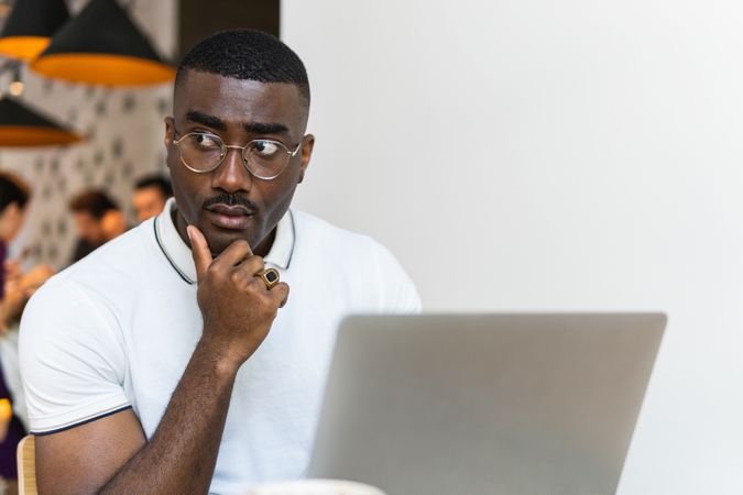 Serious Black man using laptop at table in cafe