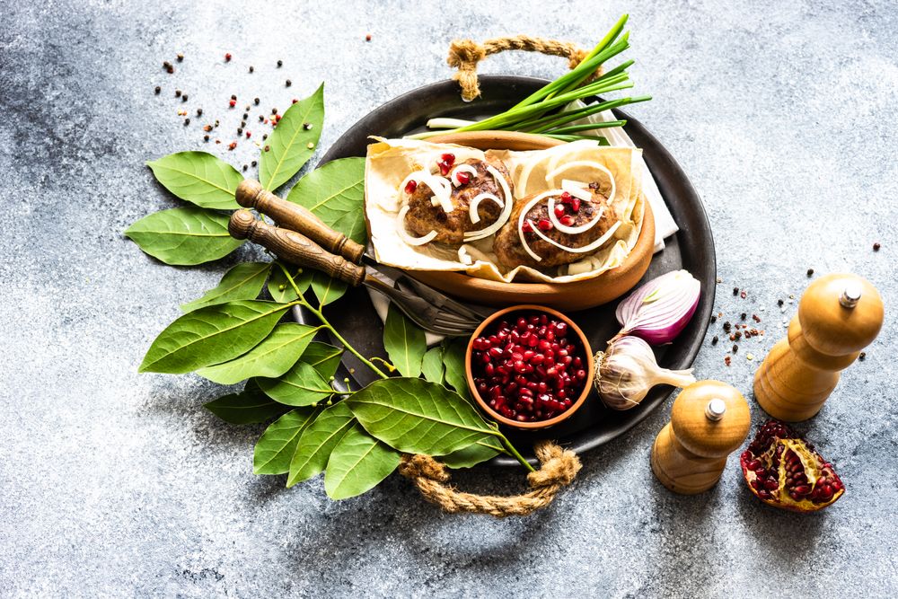Top view of Georgian dish of abkhazura meat cutlets on plate with spring onions & pomegranate seeds