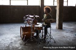 Side view of man playing drums in spacious garage bGQxB5