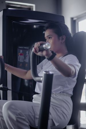 Focused woman enhances chest power utilizing pressing machine in