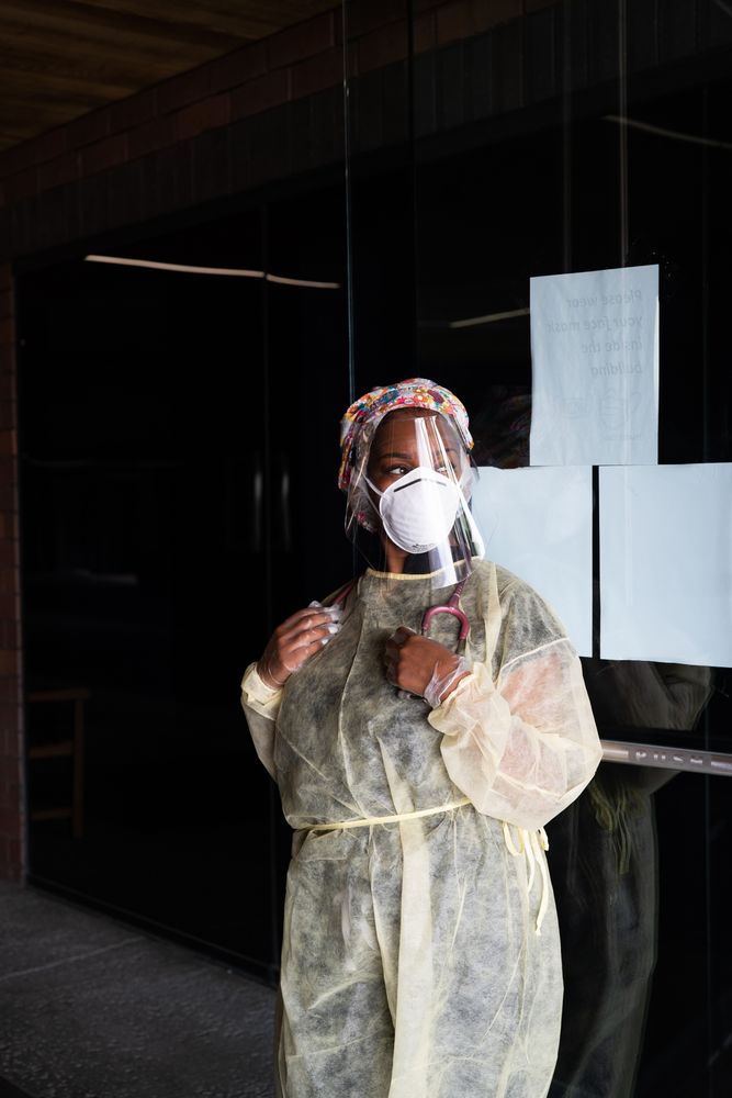 Three quarter shot of woman nurse wearing PPE standing in front of office door