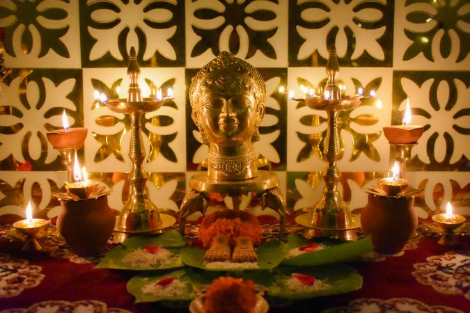Buddha figurine surrounded by diyas and flowers on a table