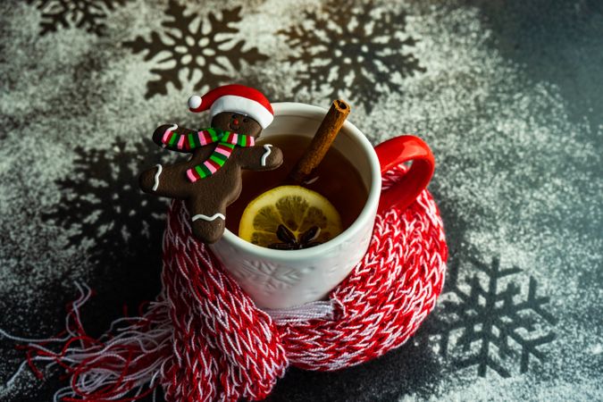 Cup of mulled tea wrapped in cosy scarf with gingerbread cookie