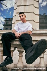 Stylish young man in light t-shirt sitting on stoop in London 0yPQLb