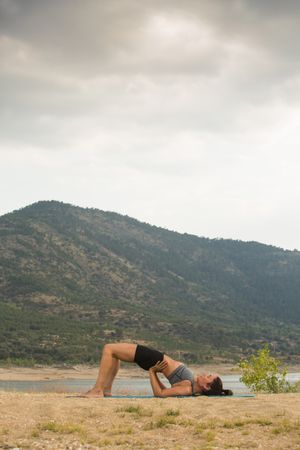 Woman practicing yoga outdoors near water