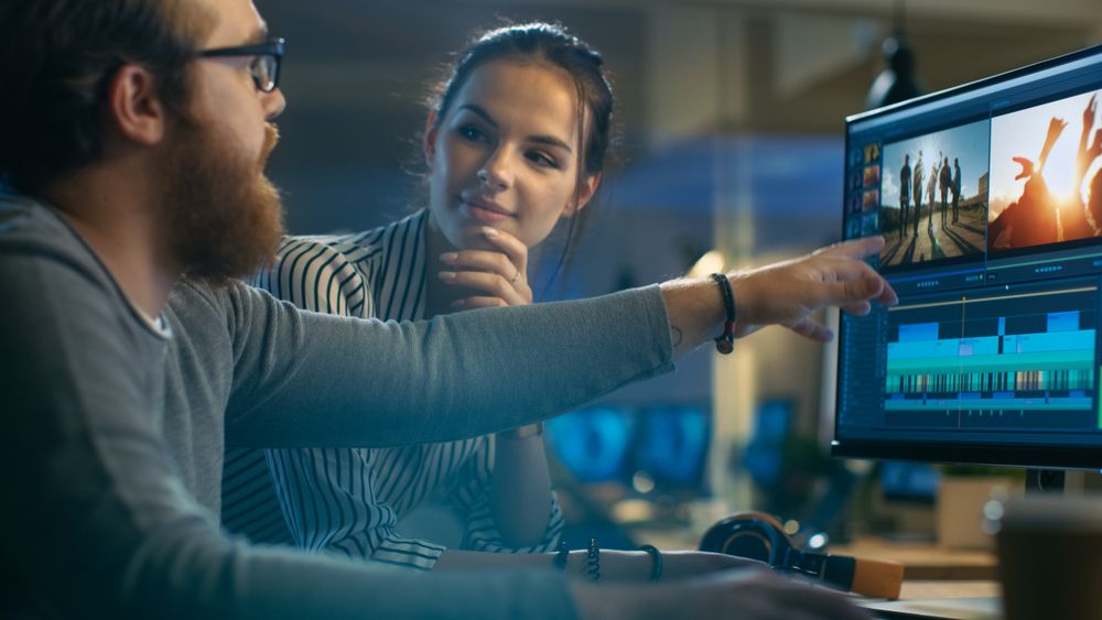 Female and Male Video Editors Work With Footage and Sound on Their Personal Computer with Two Displays.