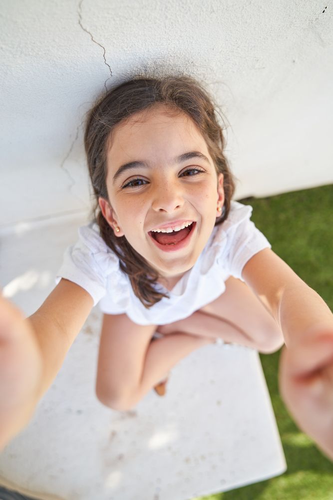 Excited girl sitting near concrete wall