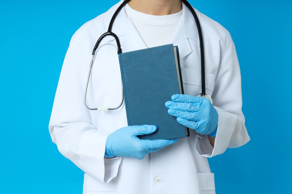 Female doctor holds book on blue background