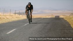 Professional athlete riding bike on countryside highway bGRArY