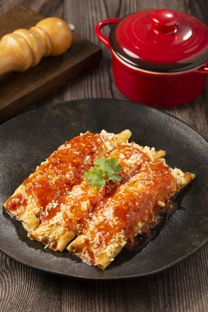 Pancakes stuffed with minced meat and topped with tomato sauce and grated cheese.