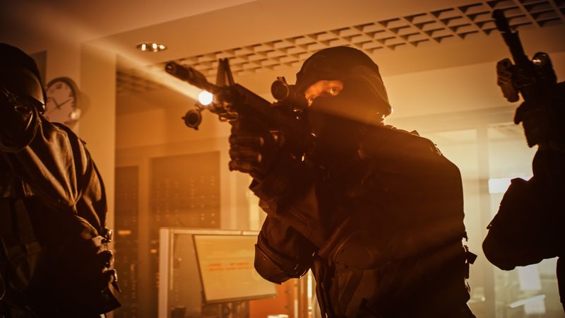 Masked Team of Armed SWAT Police Officers Move in a Hall of a Dark Seized Office Building with Desks and Computers.