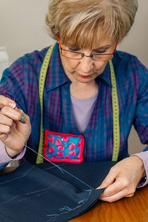 Mature female seamstress sewing cloth