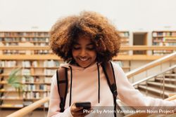 Female student smiling while texting in library 41x2g5