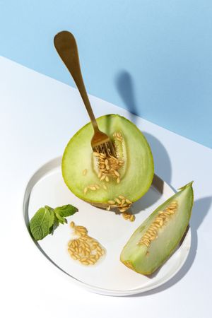 Sliced small melon on plate with spoon and fork