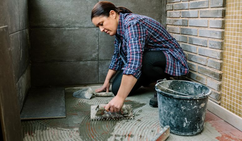 Female mason laying tiles on a terrace