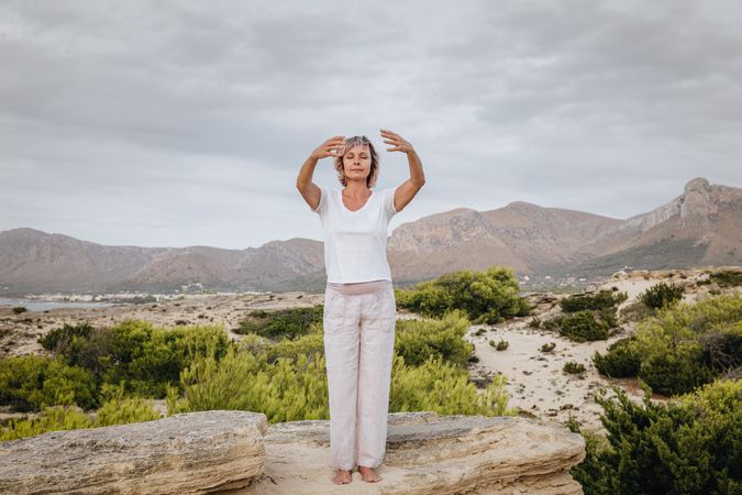 Barefoot woman meditating on stone