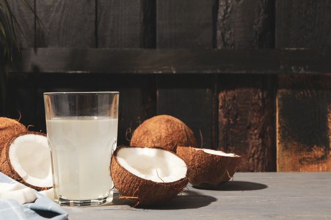Coconut and water on wooden background, space for text. Tropical fruit