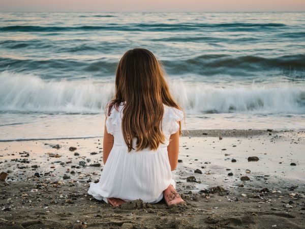 back view girl sitting on beach in daylight