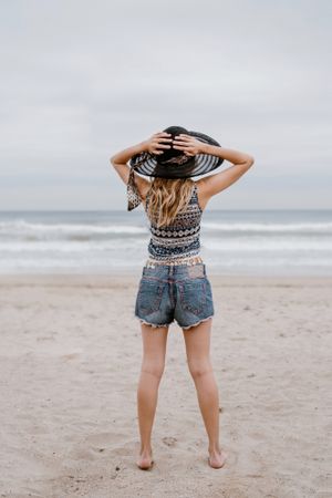 Young female relaxing on beach with hat