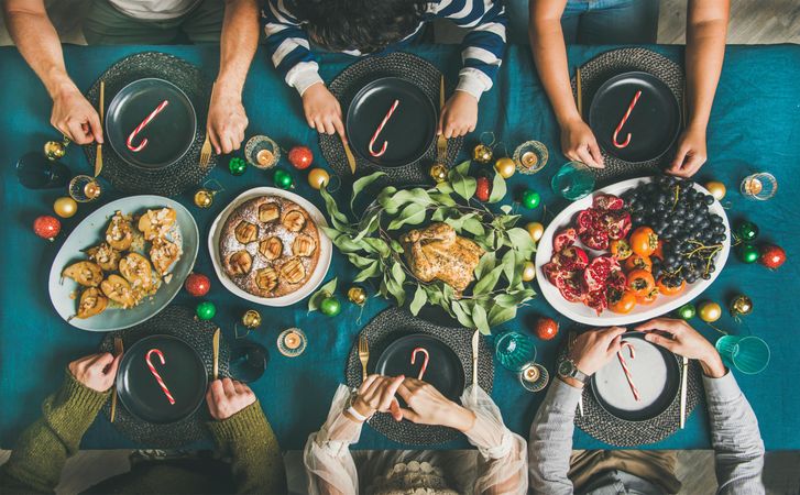 Group of people at festive table with candy canes  on each plate