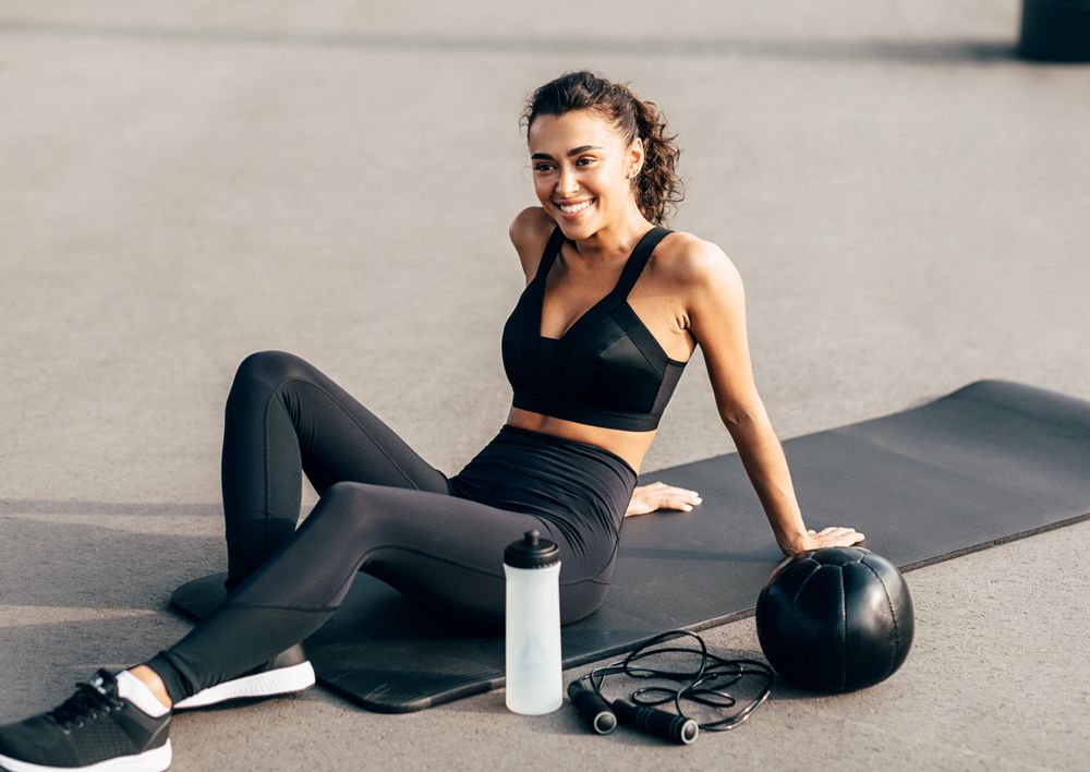 Fit woman in workout gear resting on yoga mat