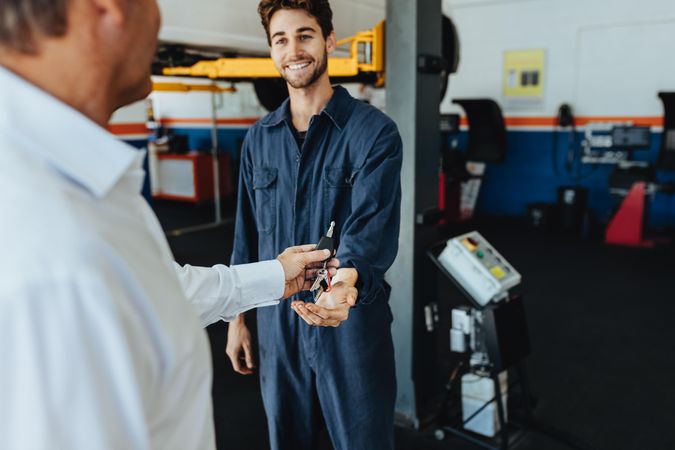Customer giving his car keys to mechanic at the repair garage