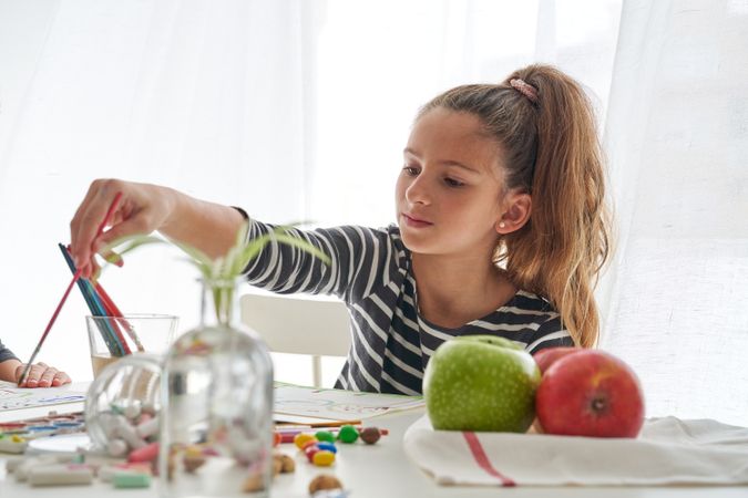 Girl painting at table with apples