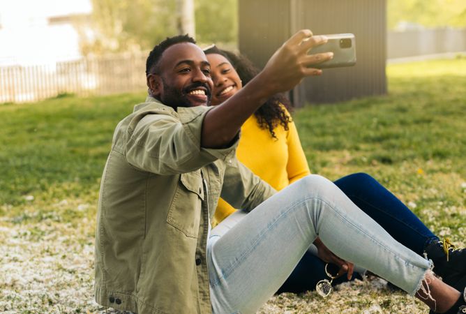 Black couple taking a selfie sitting on the grass