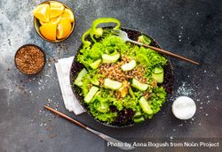 Top view of green fresh salad on concrete background served with flax seed and lemon slices with copy space 0Ldrxe