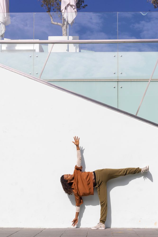 Woman in athletic wear stretching before running against wall