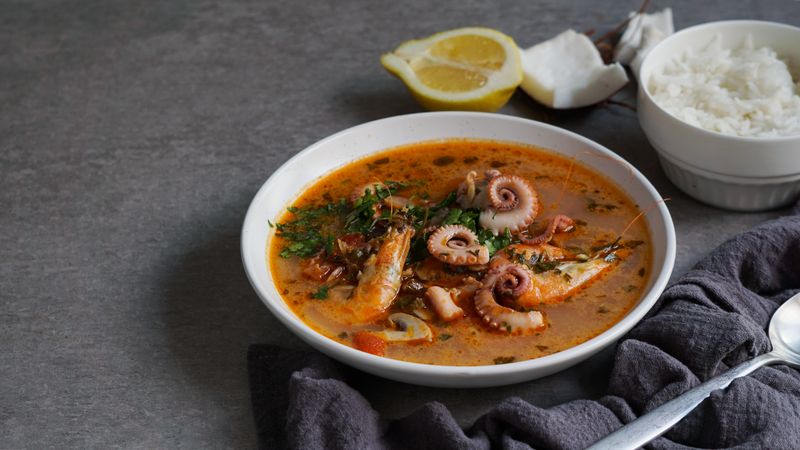 Soup of octopus and shrimps near rice and lemon